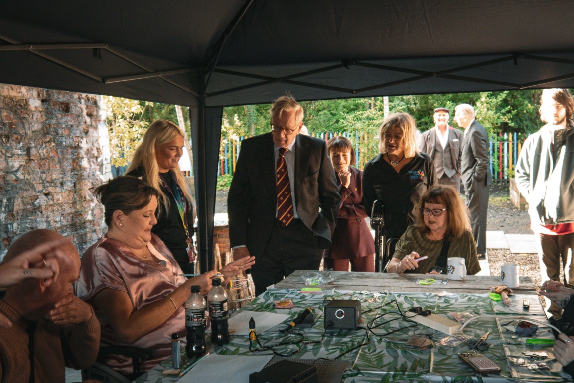 The Duke of Gloucester watches a craft group in the garden