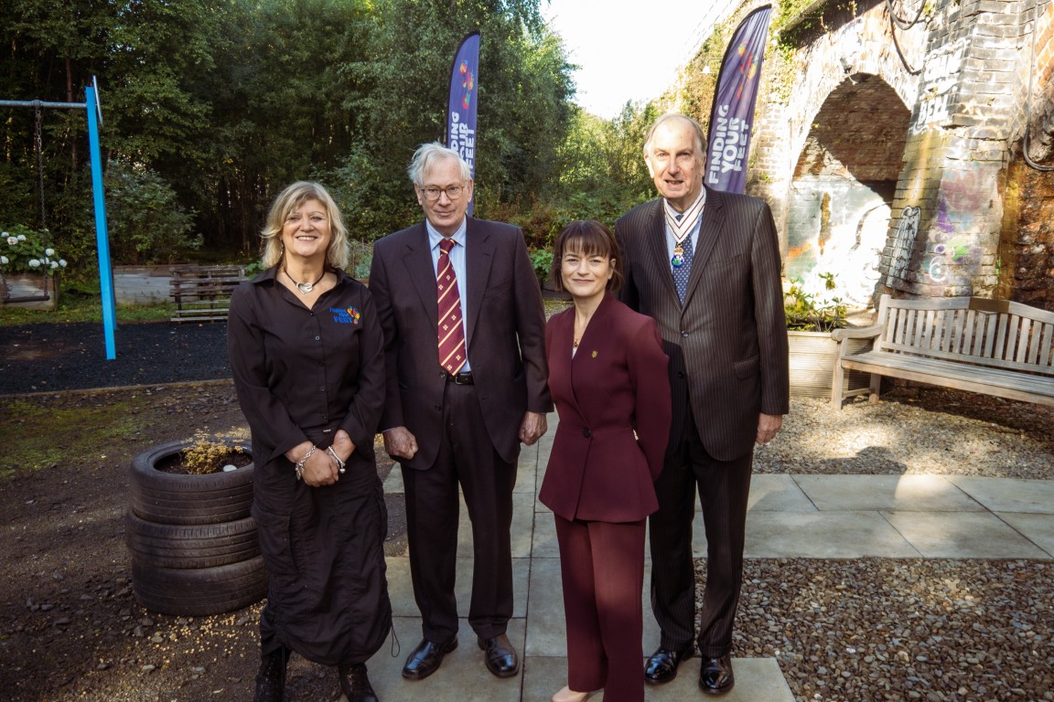 Four people pose for a photograph in the garden