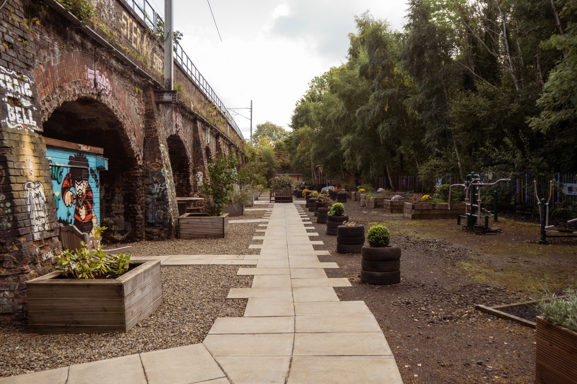 Path and planters in the Finding Your Feet garden beneath railway arches