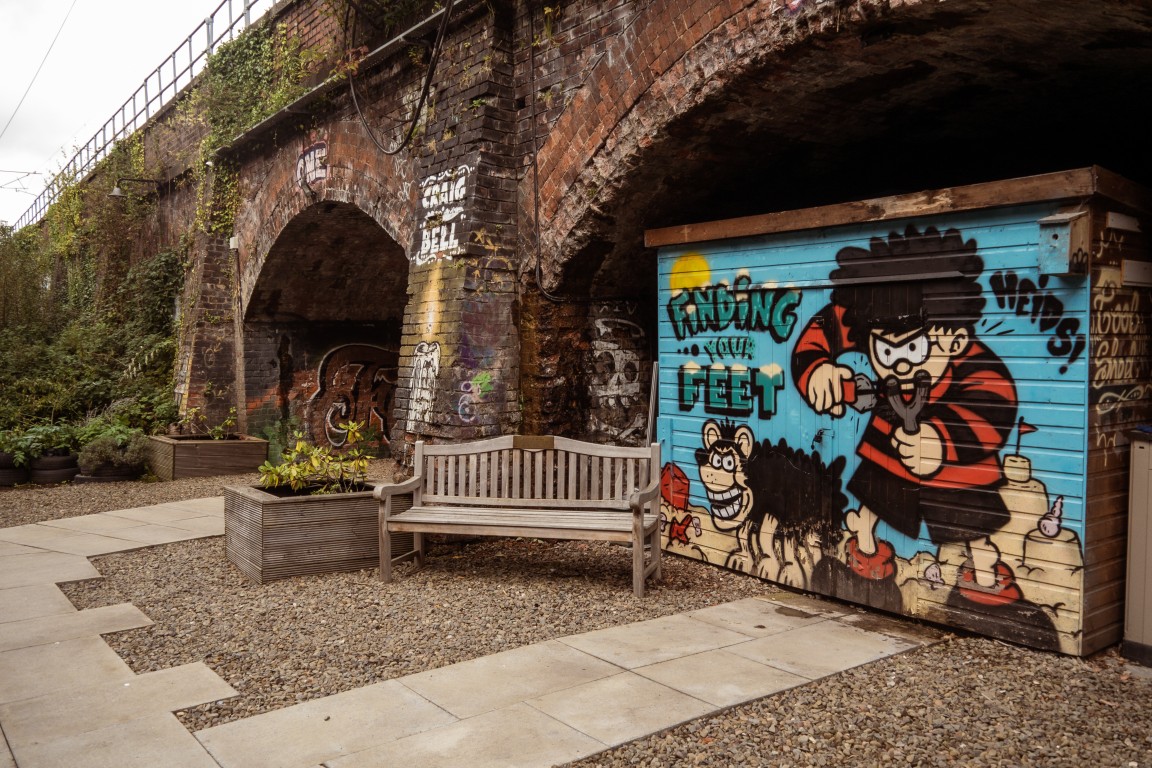 Bench and mural beneath a railway arch in the garden