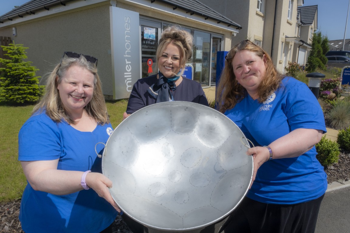 Members of the Wee County Community Saltire Steel Band with a Miller Homes representative