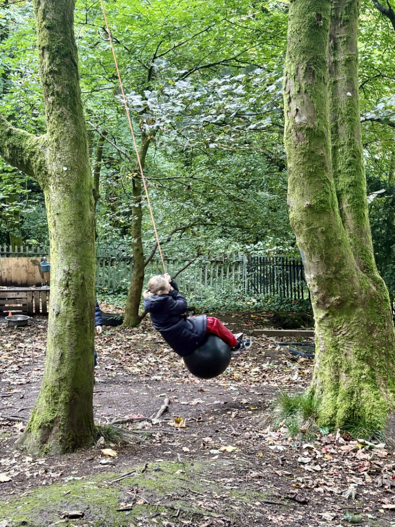 Pupil enjoying a rope swing in the outdoor learning area at Bridge of Weir Primary School
